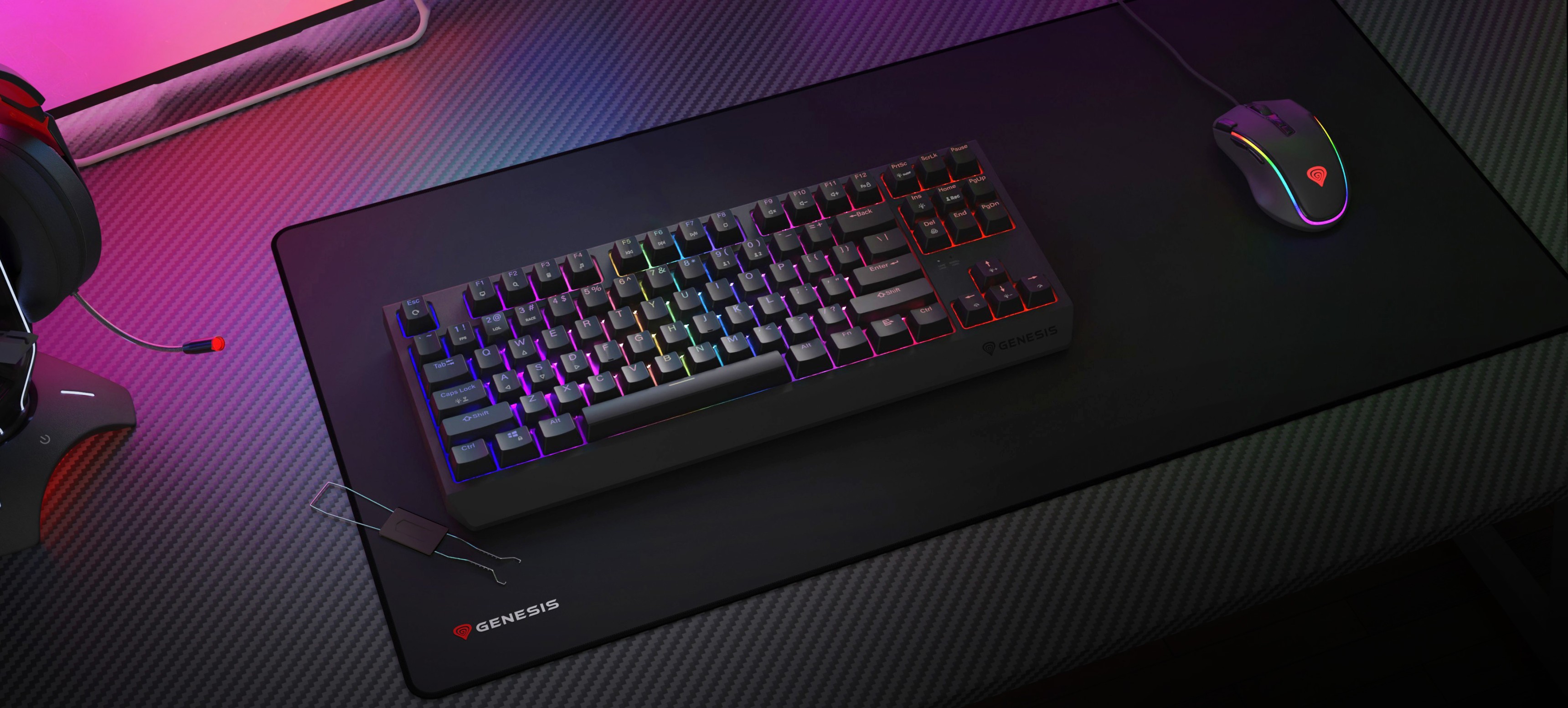 Беспроводная механическая игровая клавиатура с RGB-подсветкой, расположенная на большом коврике рядом с игровой мышью и гарнитурой